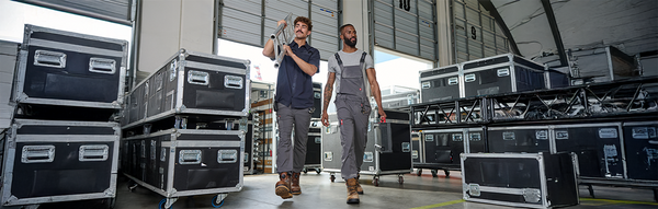 Two men wearing workwear and carrying tools