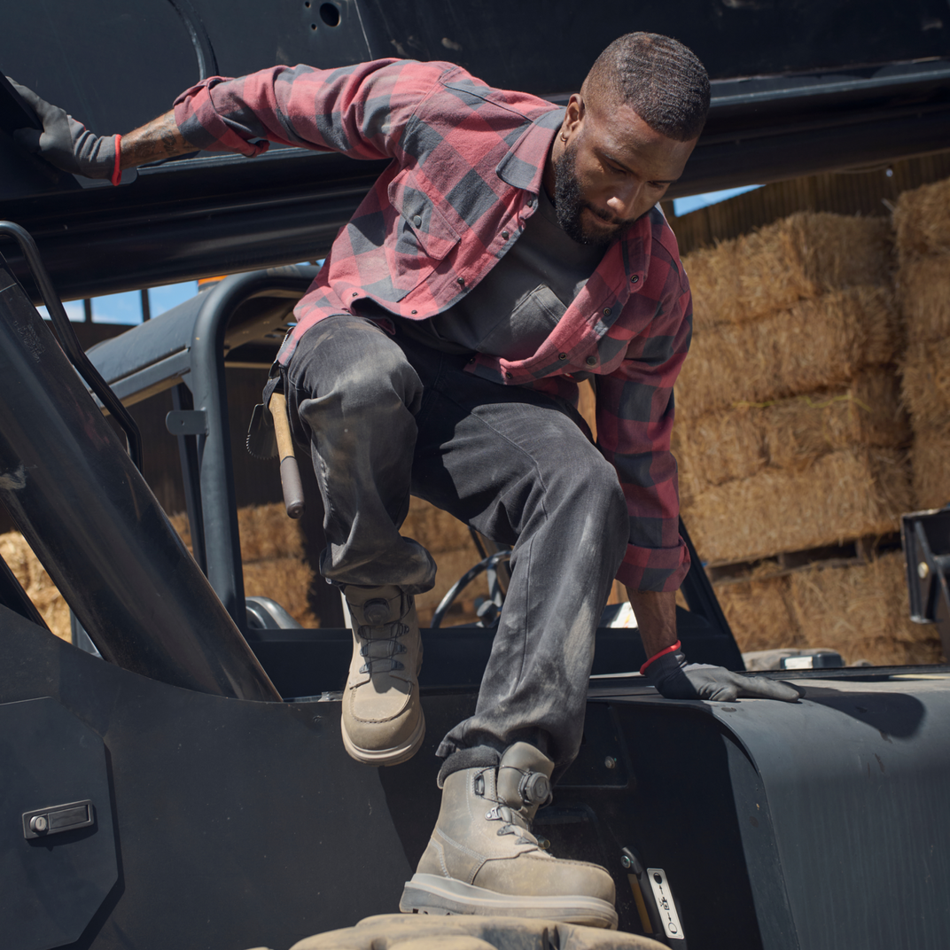 Man climbing out of a black vehicle with hay bales in the background