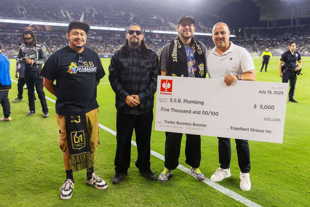 Last year's Business Booster Contest winners standing on a soccer pitch, holding a $5,000 check