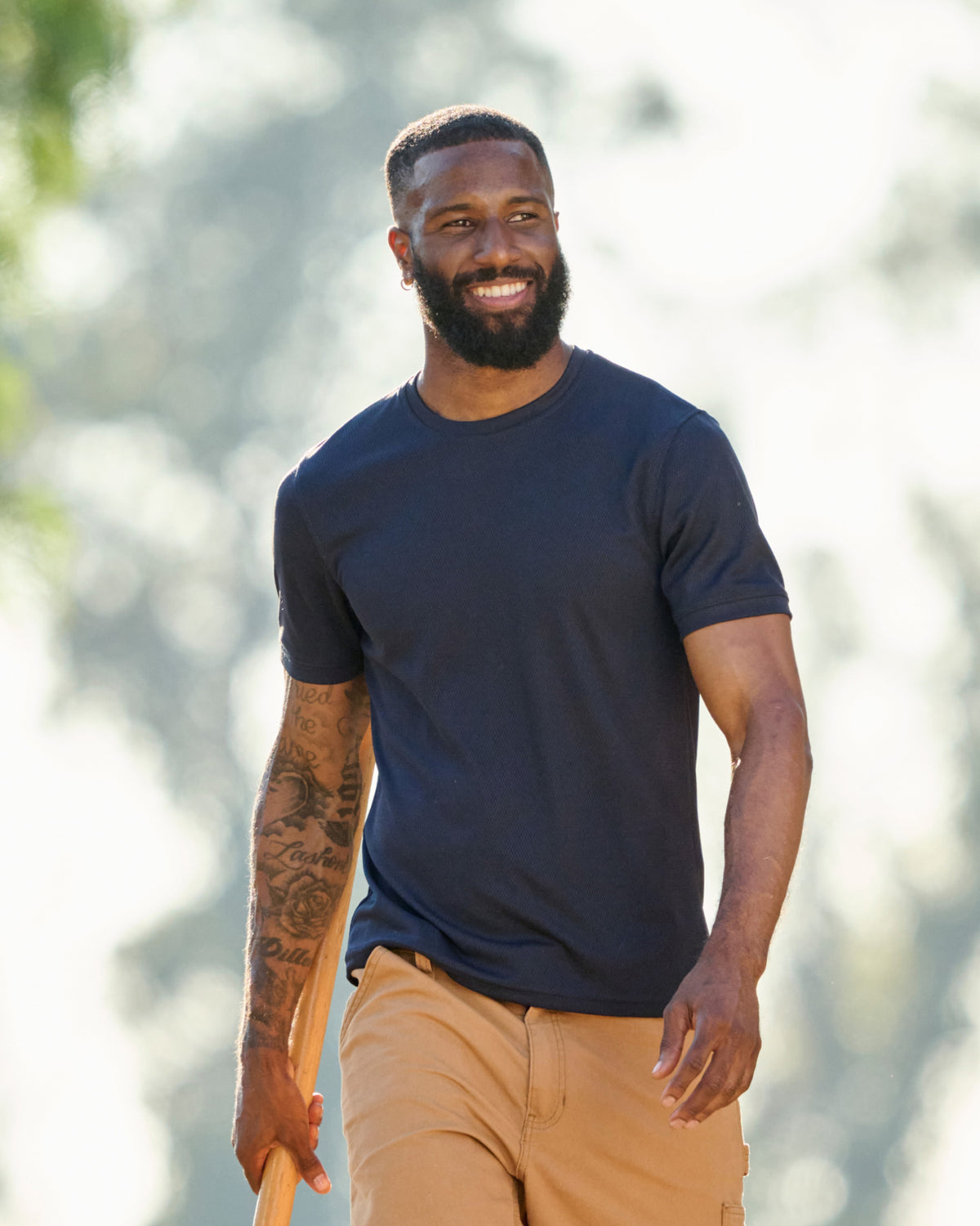 A worker wears the STRAUSS Performance T-Shirt in nero blue on a sunny jobsite