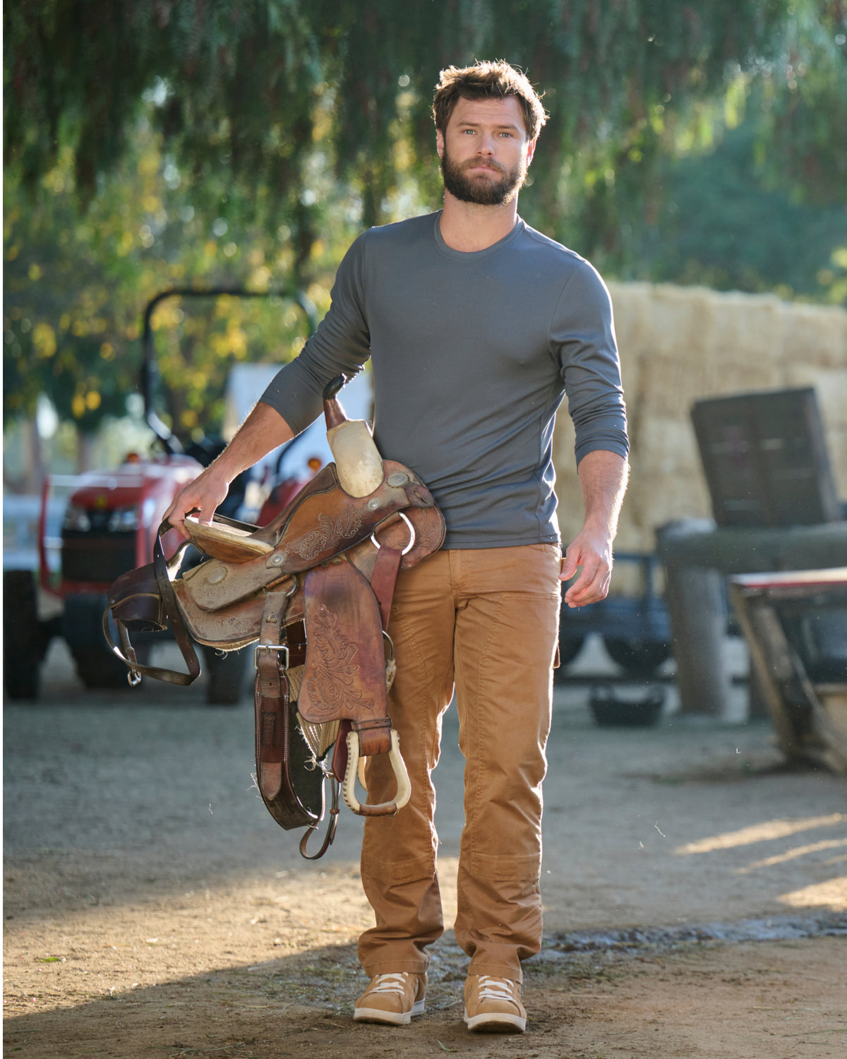 A worker wears the STRAUSS Performance Long Sleeve Shirt in carbon gray with tan work pants beside jobsite equipment