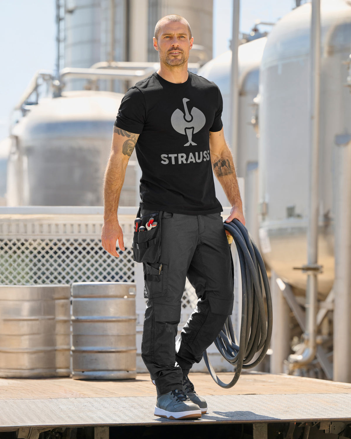 A model wears the STRAUSS T-Shirt e.s.concrete in black with matching work pants in a monochrome workwear outfit