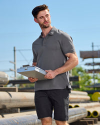 A worker wears the STRAUSS Cotton Stretch Polo Shirt in carbon gray with tan work pants on a sunny jobsite