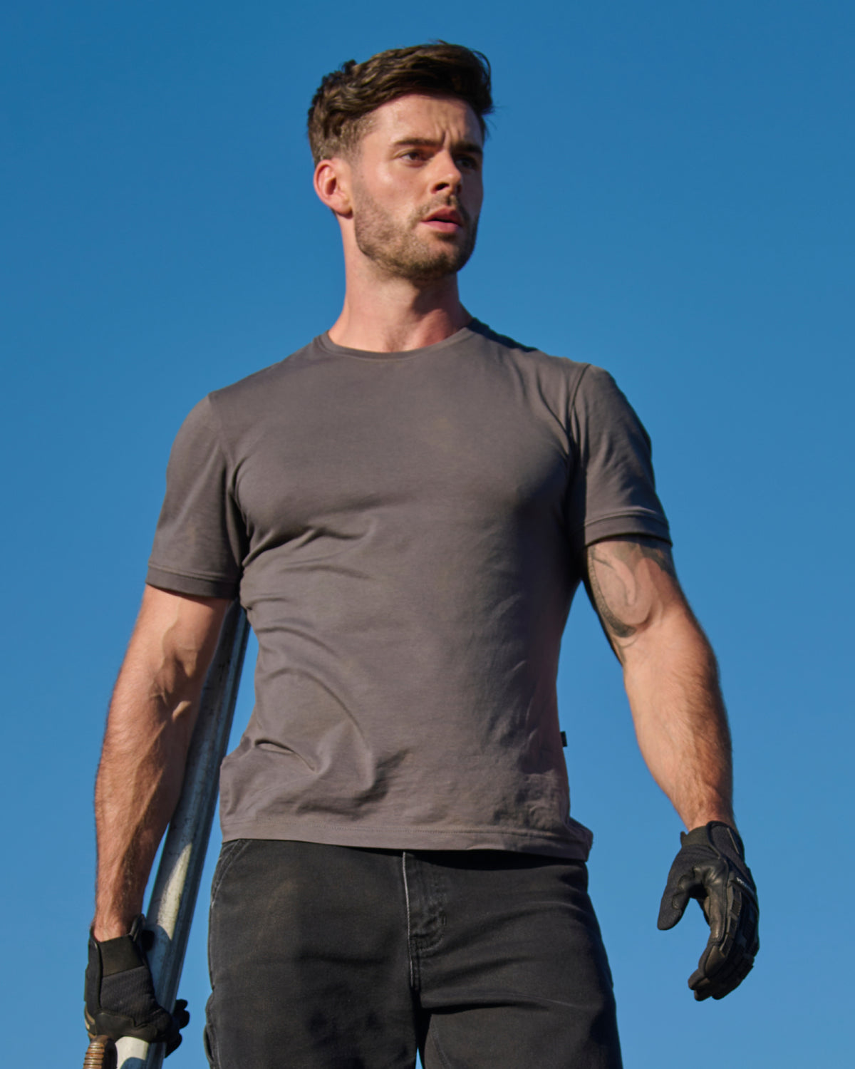 A worker wears the STRAUSS Cotton Stretch T-Shirt in carbon gray on a sunny jobsite
