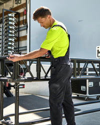 black STRAUSS Stretch Ripstop Cargo Work Bib Overall e.s.taktik shown in use at a jobsite
