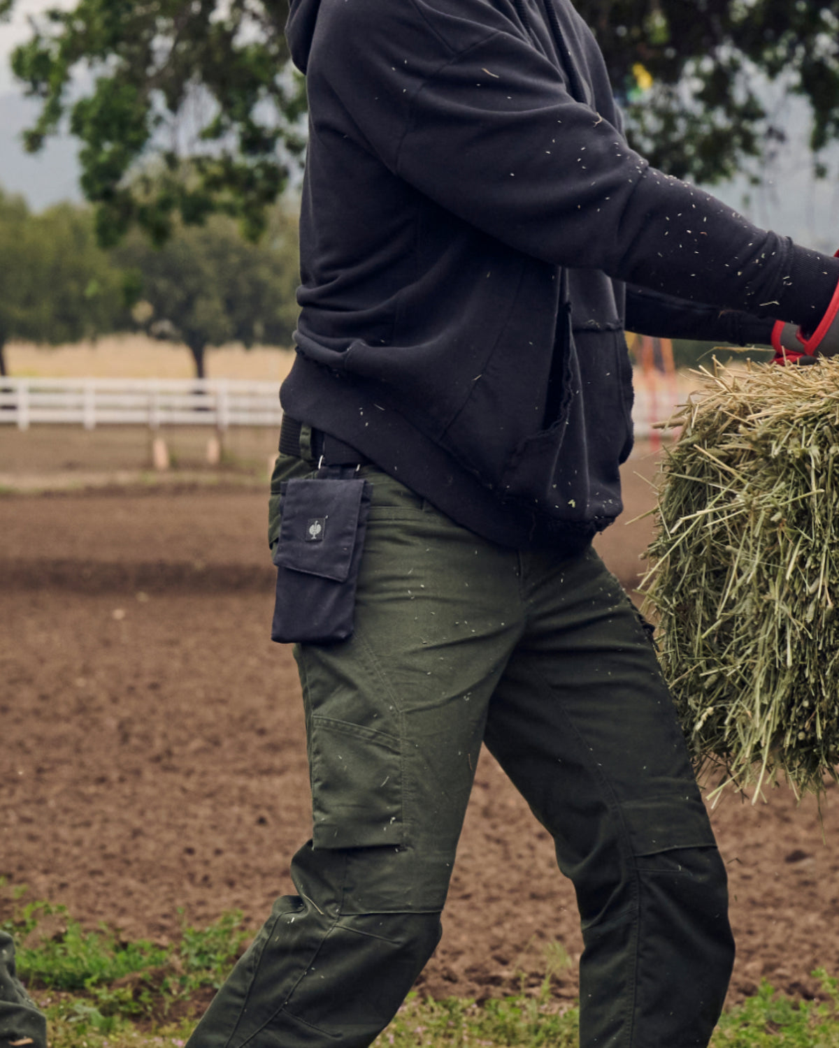A close work scene shows a oxid black STRAUSS e.s.motion ten mobile phone pocket fastened to utility pants.