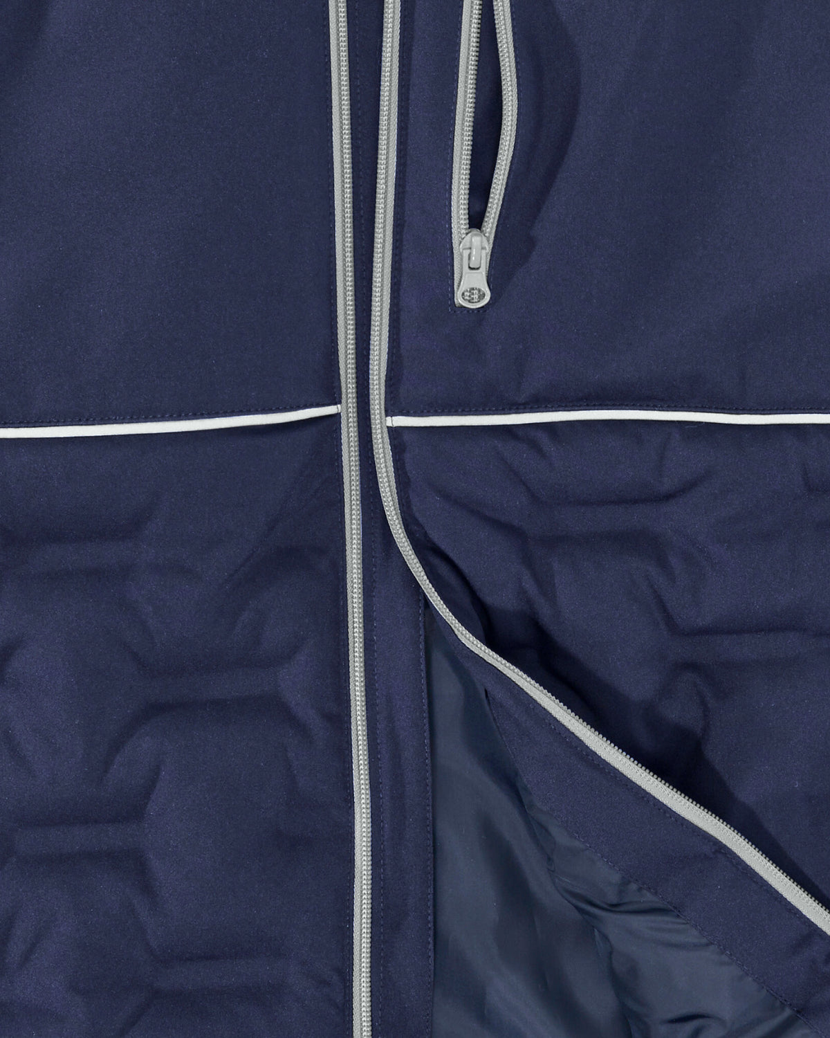Close-up of a navy blue puffer jacket showing the front zipper, a vertical zip pocket, and white piping details.