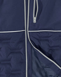 Close-up of a navy blue puffer jacket showing the front zipper, a vertical zip pocket, and white piping details.