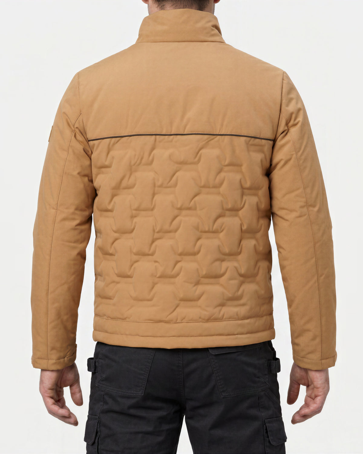 A man viewed from the back wearing a tan quilted jacket with a high collar and black cargo pants, against a light gray studio background.