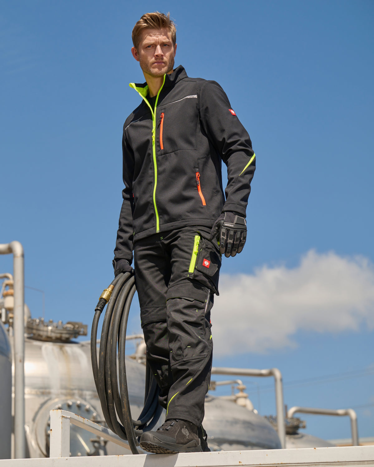 STRAUSS e.s.motion 2020 softshell jacket in black, high-vis yellow, and orange shown during outdoor work