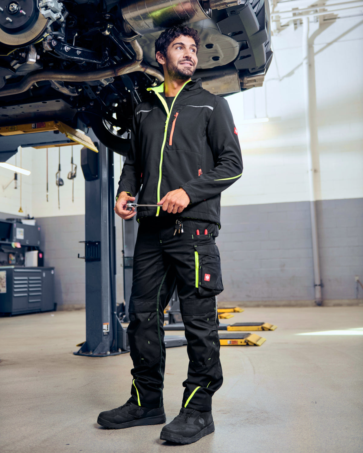 STRAUSS e.s.motion 2020 softshell jacket in black, high-vis yellow, and orange in use on the job