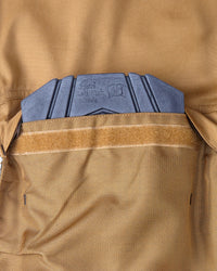 Close-up of a tan knee pad pocket with a hook-and-loop strap and a blue-gray textured pad visible at the top.