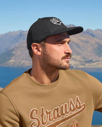 A worker in a black STRAUSS e.s.e:pic cap in outdoor workwear.