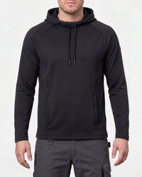 A man wearing a black long-sleeve hooded pullover with a textured knit fabric, drawstrings, and a front kangaroo pocket, paired with dark gray cargo pants, against a plain white background.