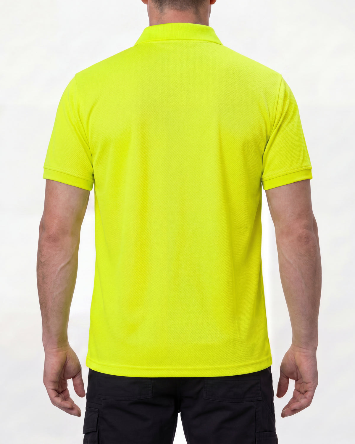 A model wears the STRAUSS Enhanced Visibility Performance Polo Shirt in neon yellow with dark work pants and work boots, showing the shirt fit