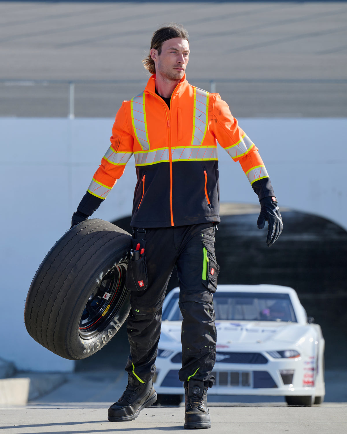STRAUSS Class 2 high visibility softshell jacket in neon orange and black shown on an outdoor jobsite