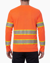 A model wears the STRAUSS Class 2 High Visibility Long Sleeve Shirt in neon orange with dark work pants and work boots, showing the shirt fit