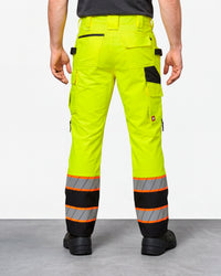 High Visibility Work Pants in neon yellow/black worn by a model, rear view