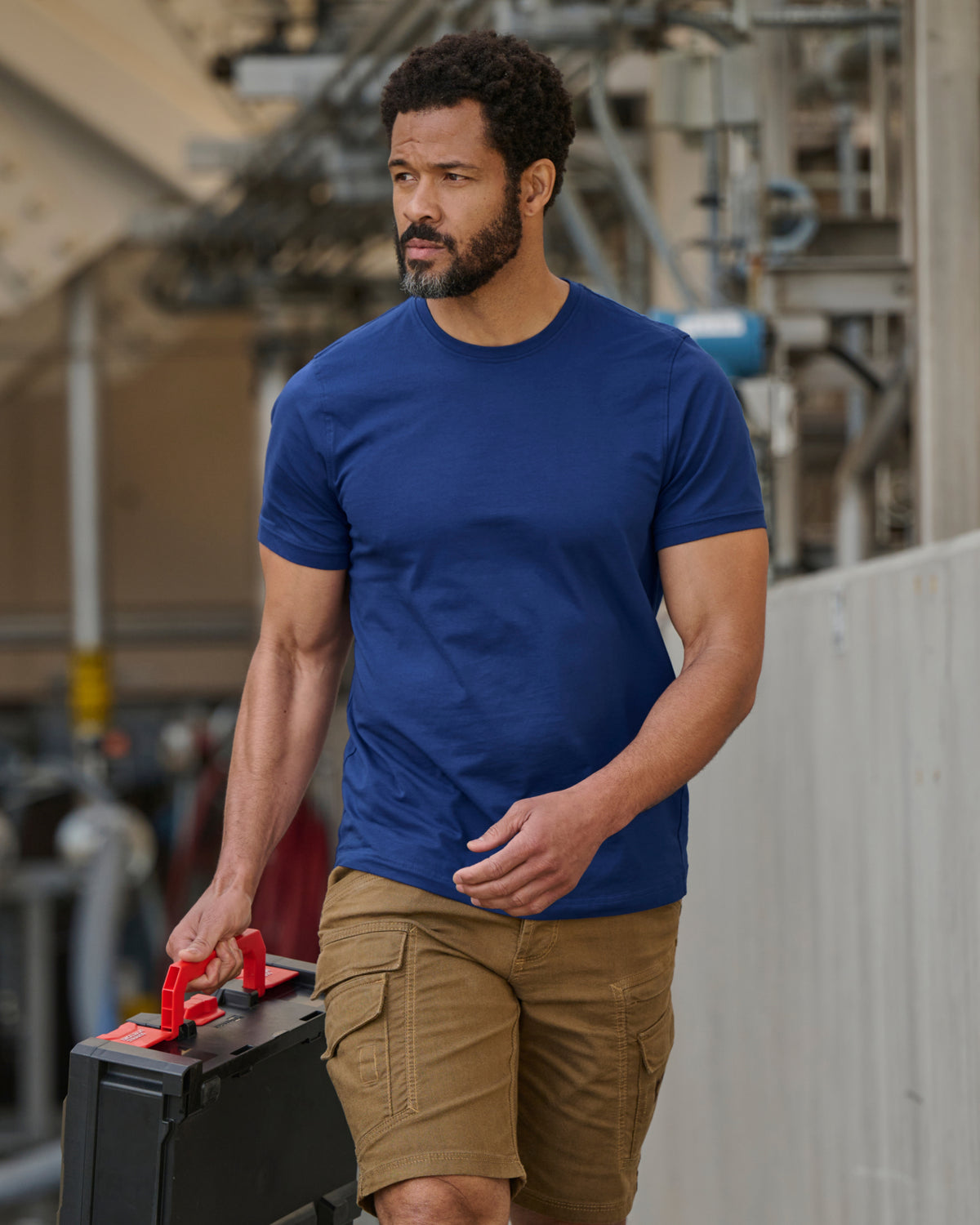 A worker wears the STRAUSS Cotton Stretch T-Shirt in royal blue with tan work pants while working