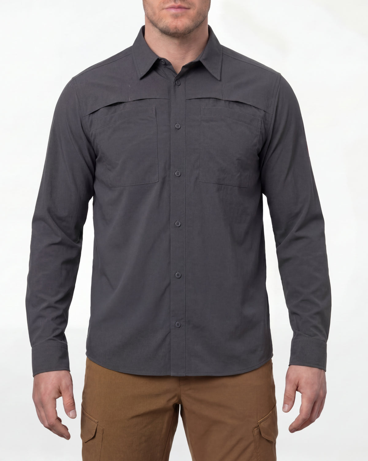 A model wears the STRAUSS e.s.taktik Stretch Ripstop Long Sleeve Work Shirt in carbon gray open over a T-shirt with work pants and work boots in a studio product scene