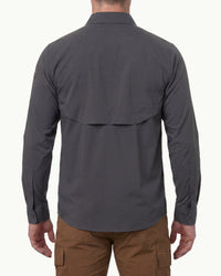 A model wears the STRAUSS e.s.taktik Stretch Ripstop Long Sleeve Work Shirt in carbon gray open over a T-shirt with work pants and work boots, showing the shirt fit