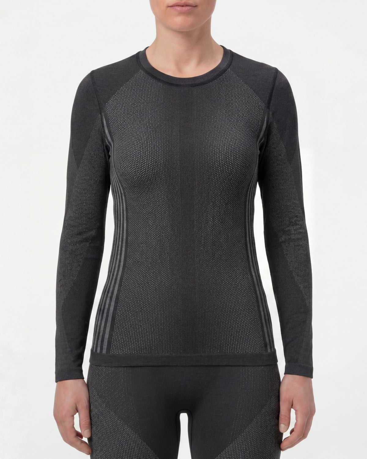 A woman wears the Women's STRAUSS e.s.trail pure Warm Seamless Thermal Long Sleeve Shirt in black and basalt gray in a studio product scene