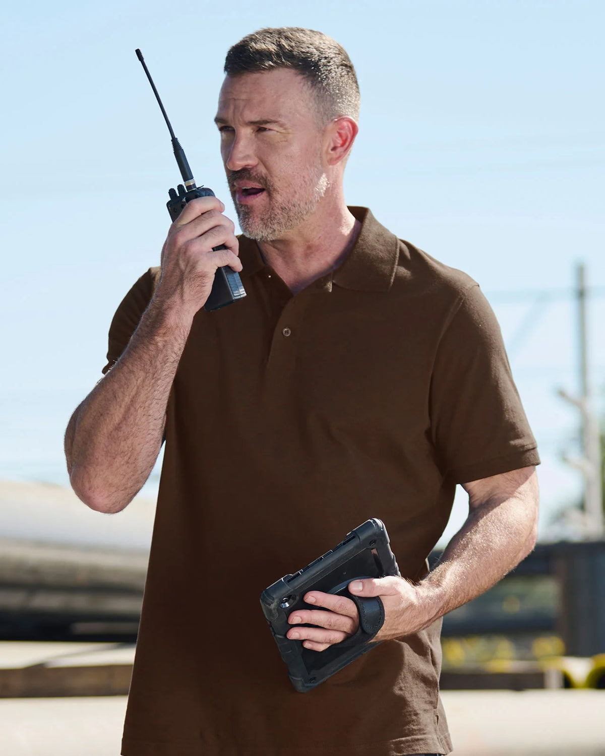 A worker wears the STRAUSS Cotton Polo Shirt in hazelnut with tan work pants on a sunny jobsite
