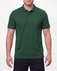 A model wears the STRAUSS Cotton Polo Shirt in green with tan work pants and work boots in a studio product scene