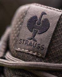 Close-up of a textured taupe woven fabric patch with a dark embroidered rooster logo and the word 'Strauss' beneath it.