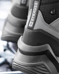 Close-up of a black and gray technical boot with a visible STRAUSS heel pull tab and textured synthetic overlays.