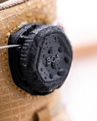 Close-up of a black waterproof cap with 'BOA' printed on it, attached to a tan fabric device covered in water droplets.