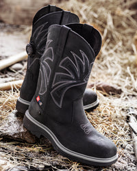 STRAUSS Doonan 12-inch Composite Toe Work Boot in Black shown on rough jobsite ground