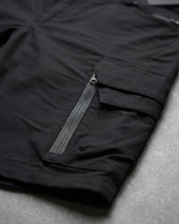 Close-up detail of Engelbert Strauss e.s. trail pure cargo work shorts in black and carbon gray, focusing on the utility pocket area, seams, and reinforced workwear construction.