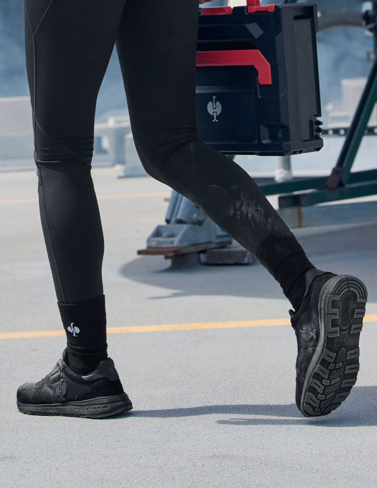 Person wearing black leggings and shoes on a concrete surface with a blurred background