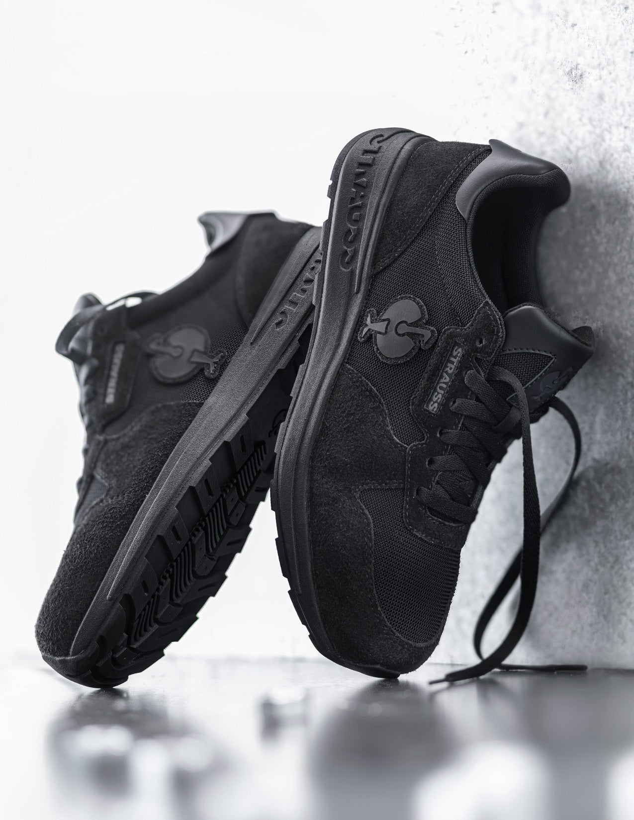 Black sneakers with a Strauss logo on a light gray background
