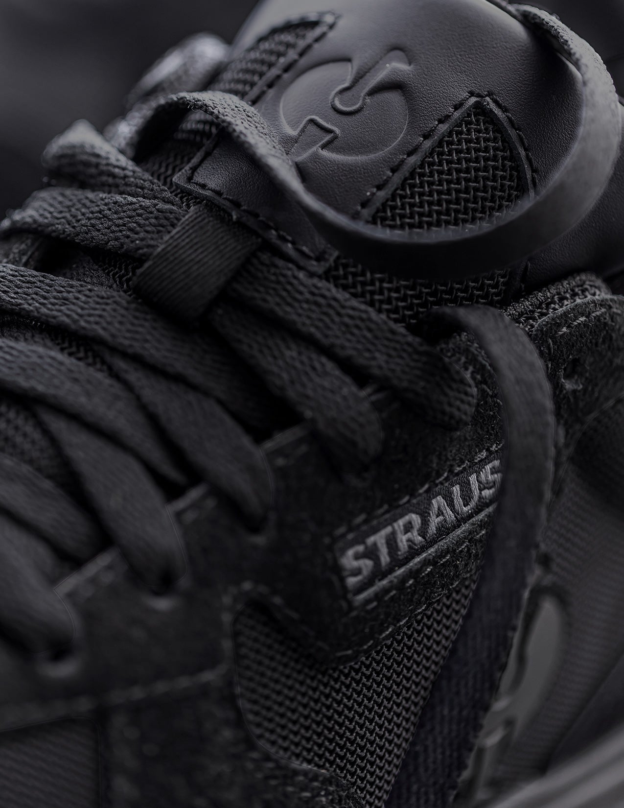Close-up of a black sneaker with visible branding on a dark background