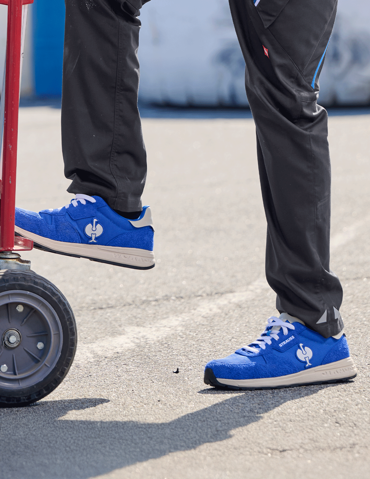Blue sneakers with white soles worn by a person standing on a concrete surface.