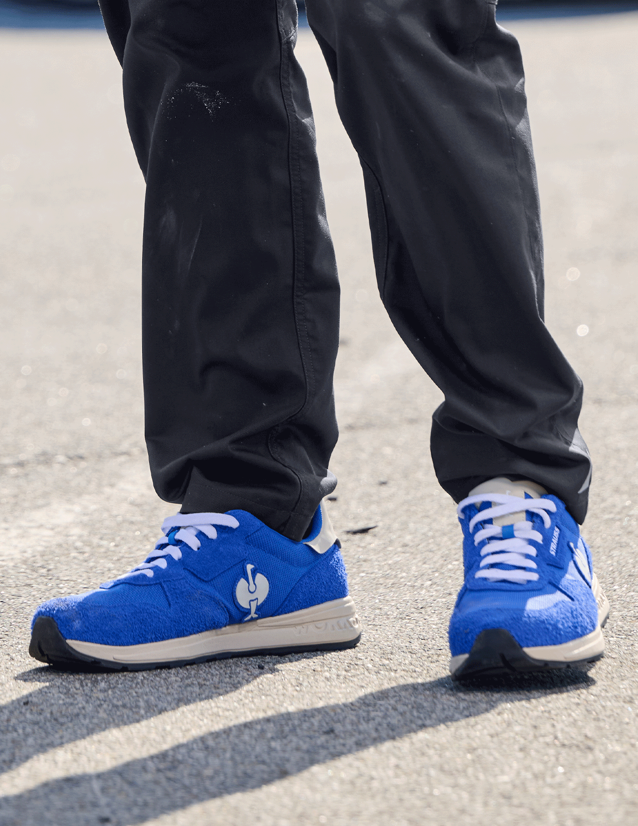 Blue sneakers with white laces worn on a concrete surface