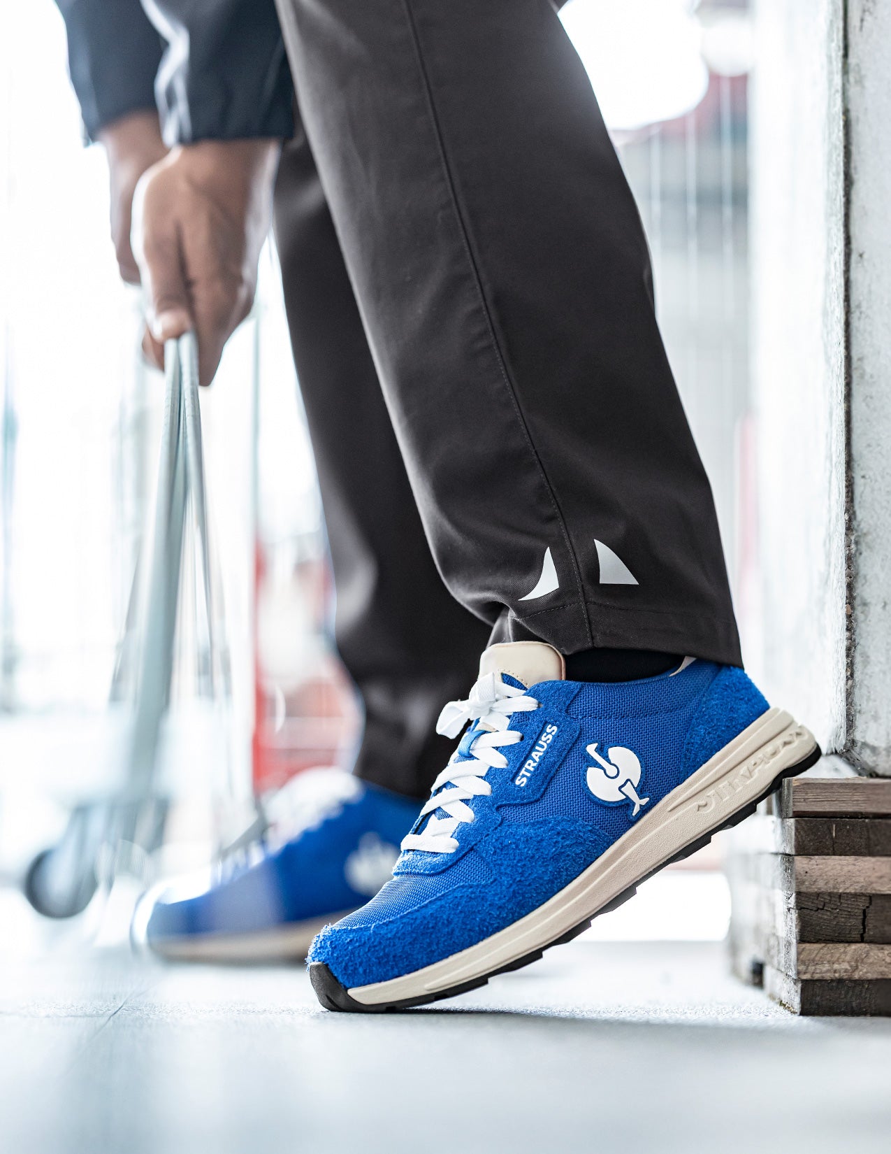 Blue sneakers with white laces worn by a person on a blurred indoor background