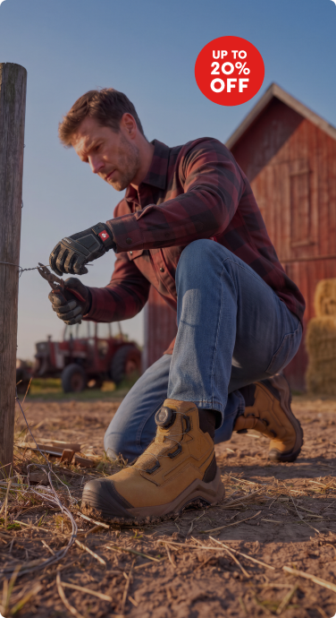 A man kneeling in front of a fence. He is wearing a red and grey flanel work shirt, a denim jeans, a pair of work boots and gloves. He is cutting a wire with a tool. At the top right corner there is a red circle with "up to 20% off" written inside.