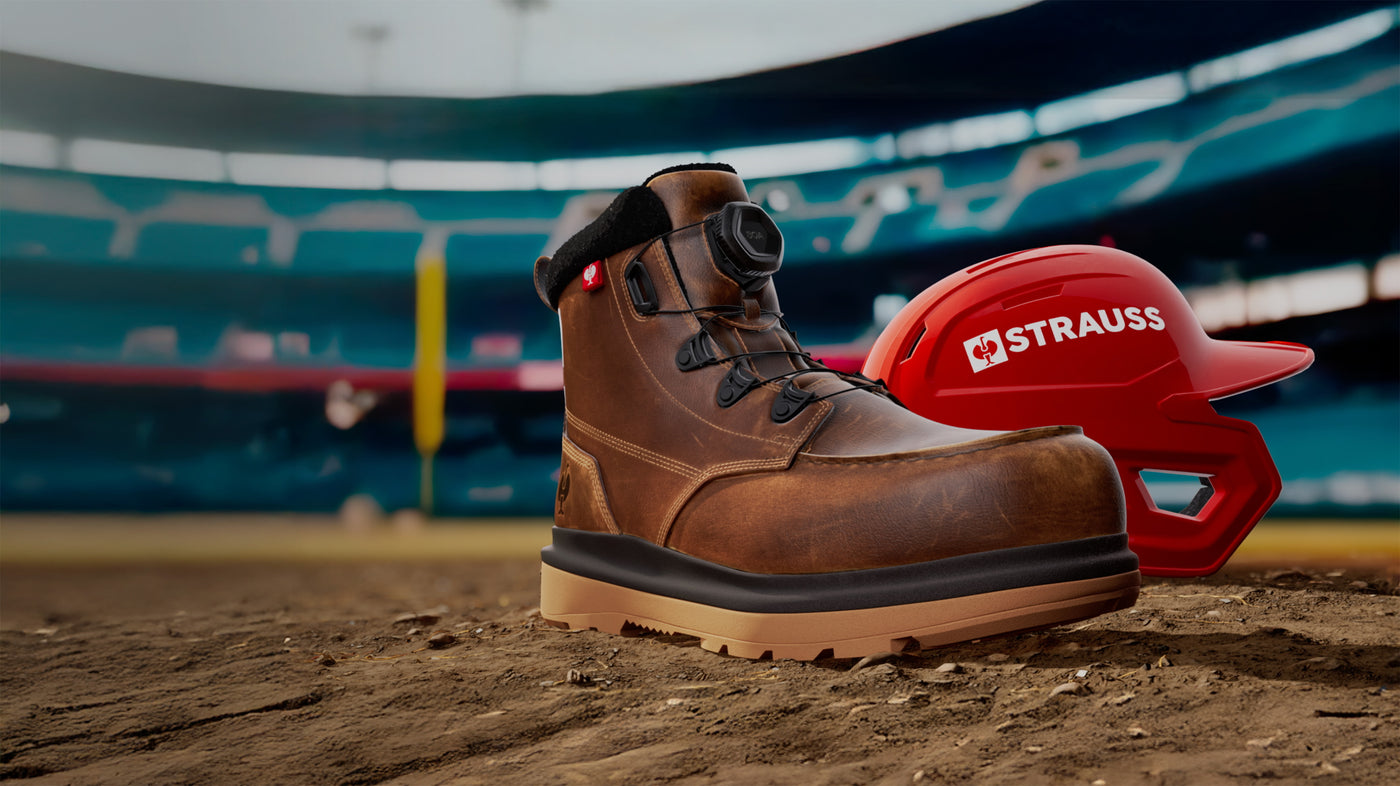 Brown work boot and red hard hat with 'Strauss' logo on a dirt surface.