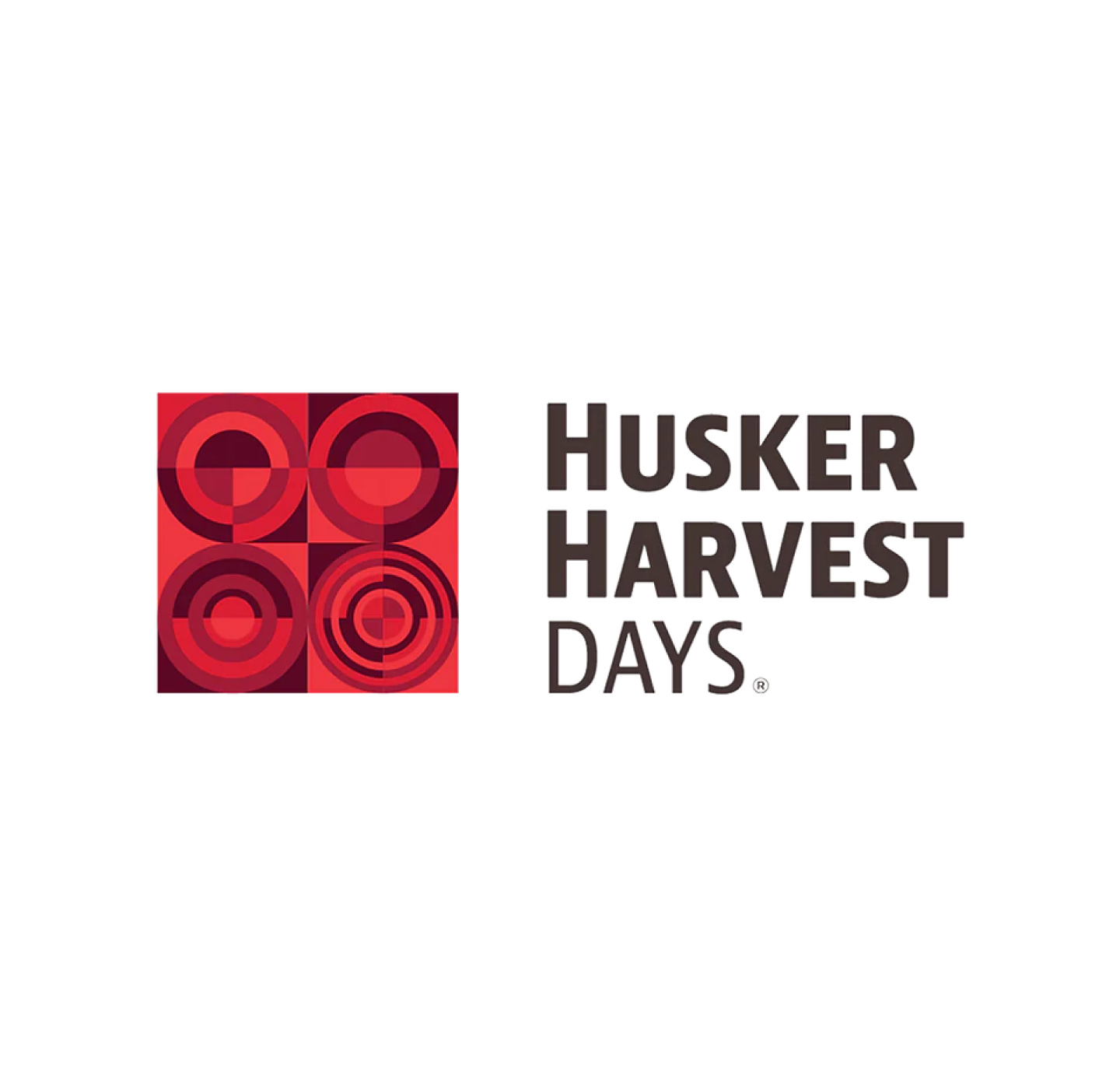 Logo with four red geometric circles on the left and the text Husker Harvest Days in bold, black letters on the right, all on a white background.
