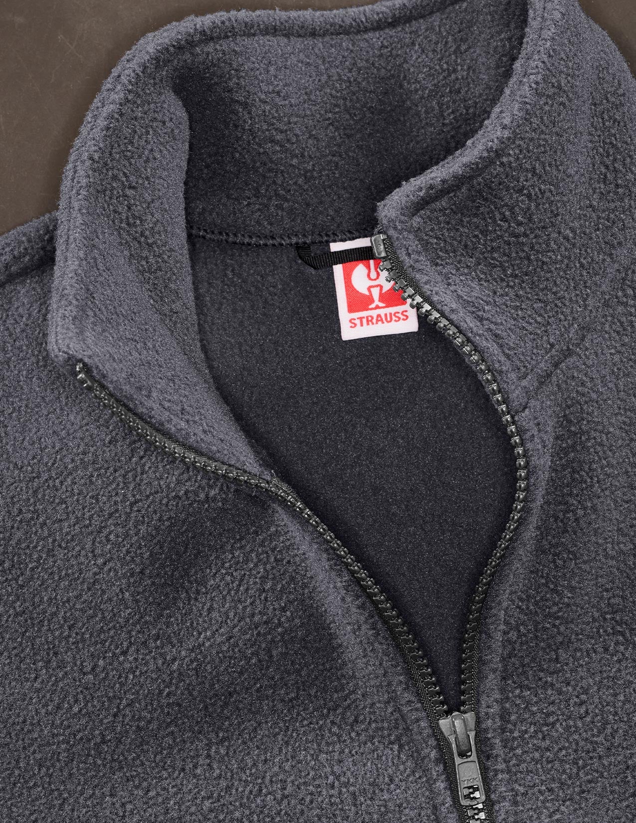 Gray fleece jacket with a visible Strauss brand label on a dark background