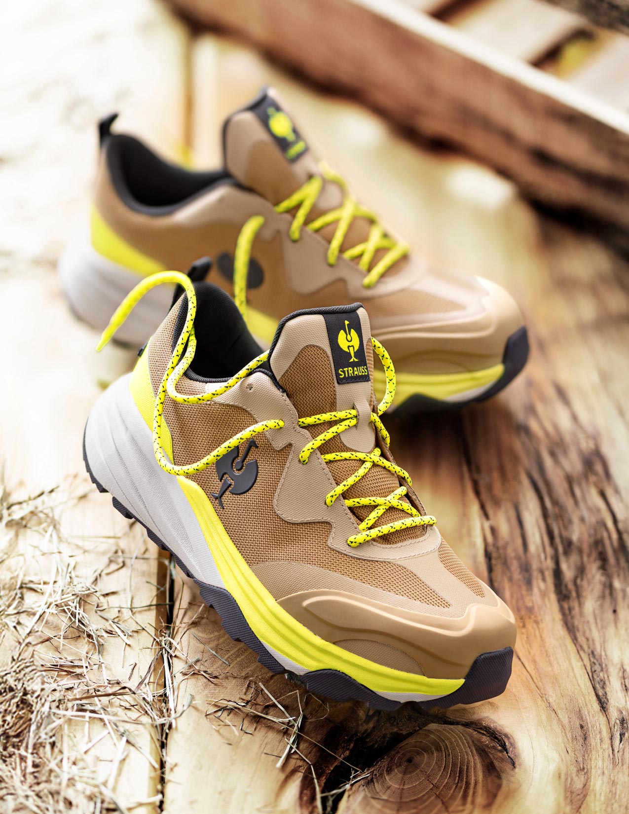 Beige and black sneakers with yellow laces on a wooden surface