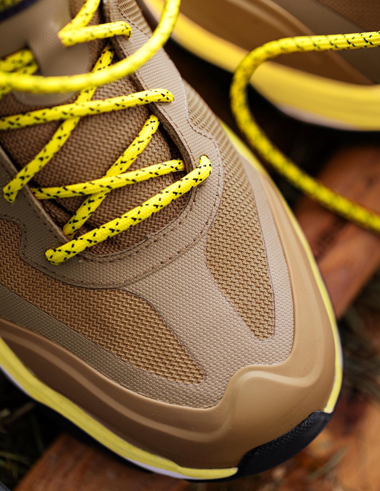 Close-up of a brown sneaker with yellow laces on a wooden surface