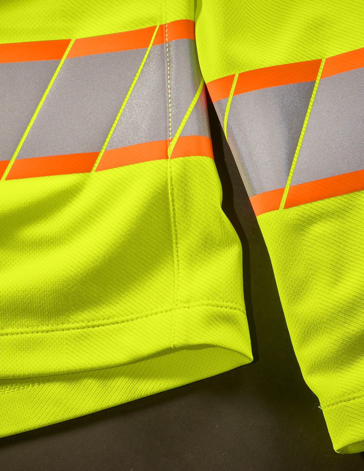 Close-up of a high-visibility safety long sleeve with reflective stripes on a dark background