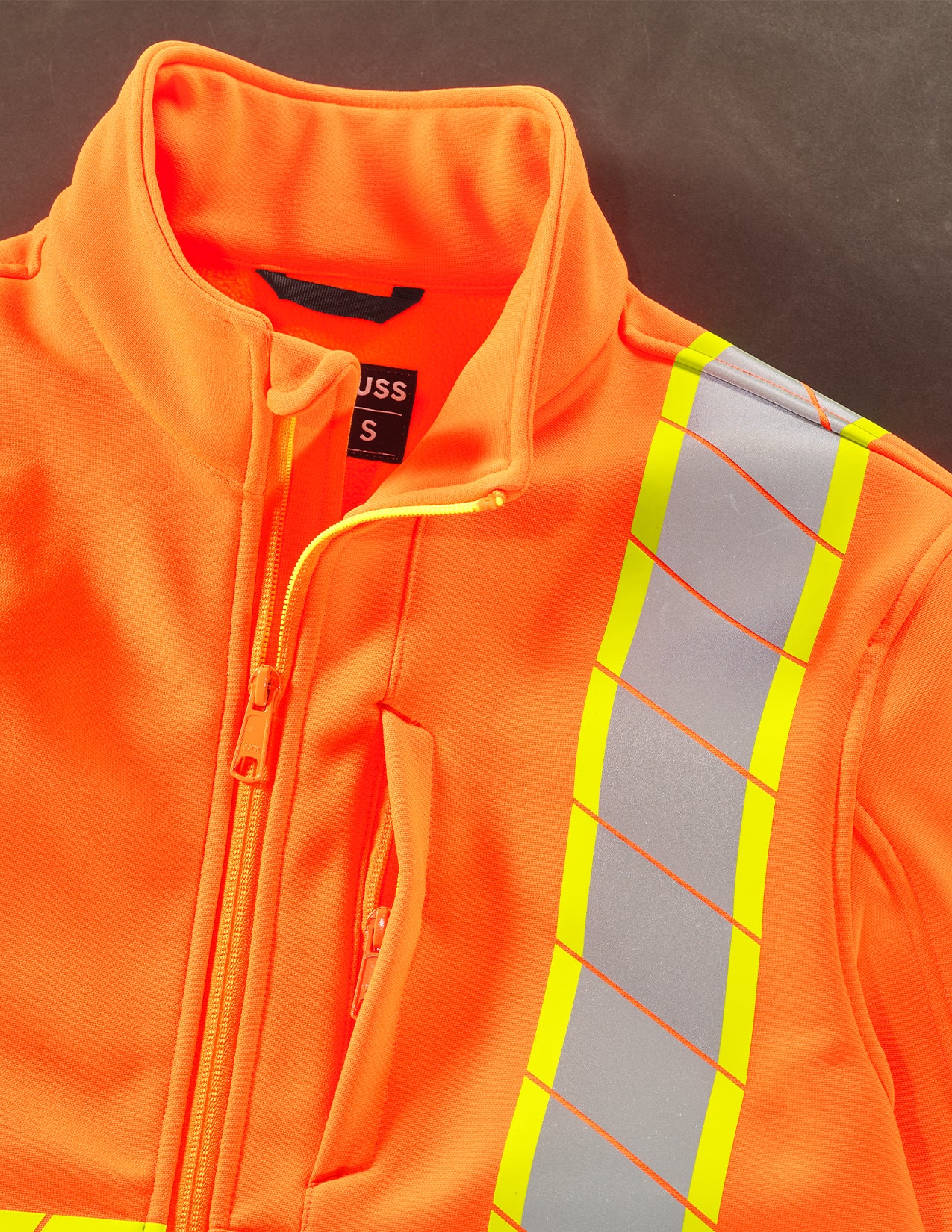 Orange safety jacket with reflective stripes on a dark background
