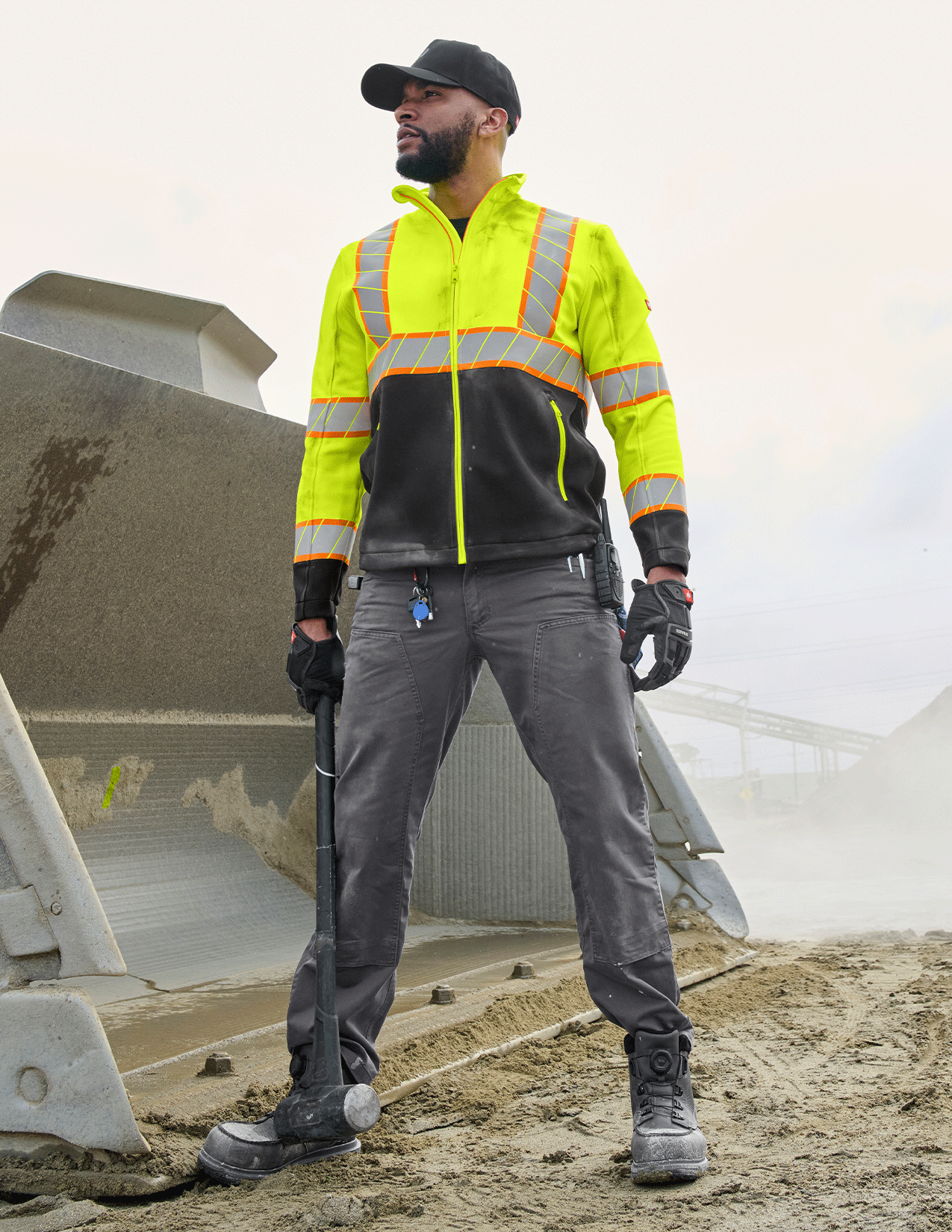 Person wearing a high-visibility safety jacket and pants on a construction site.
