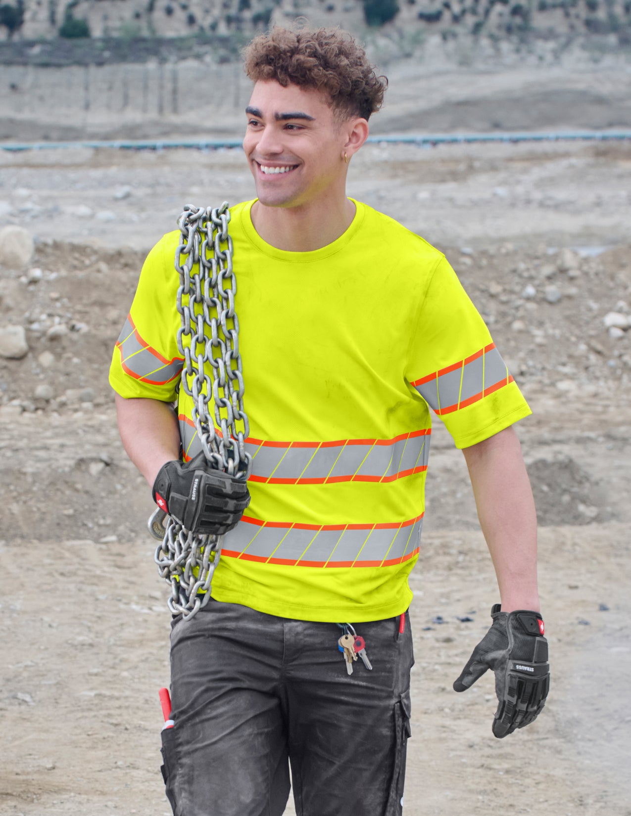 Person wearing a high-visibility safety shirt holding a chain on a construction site.