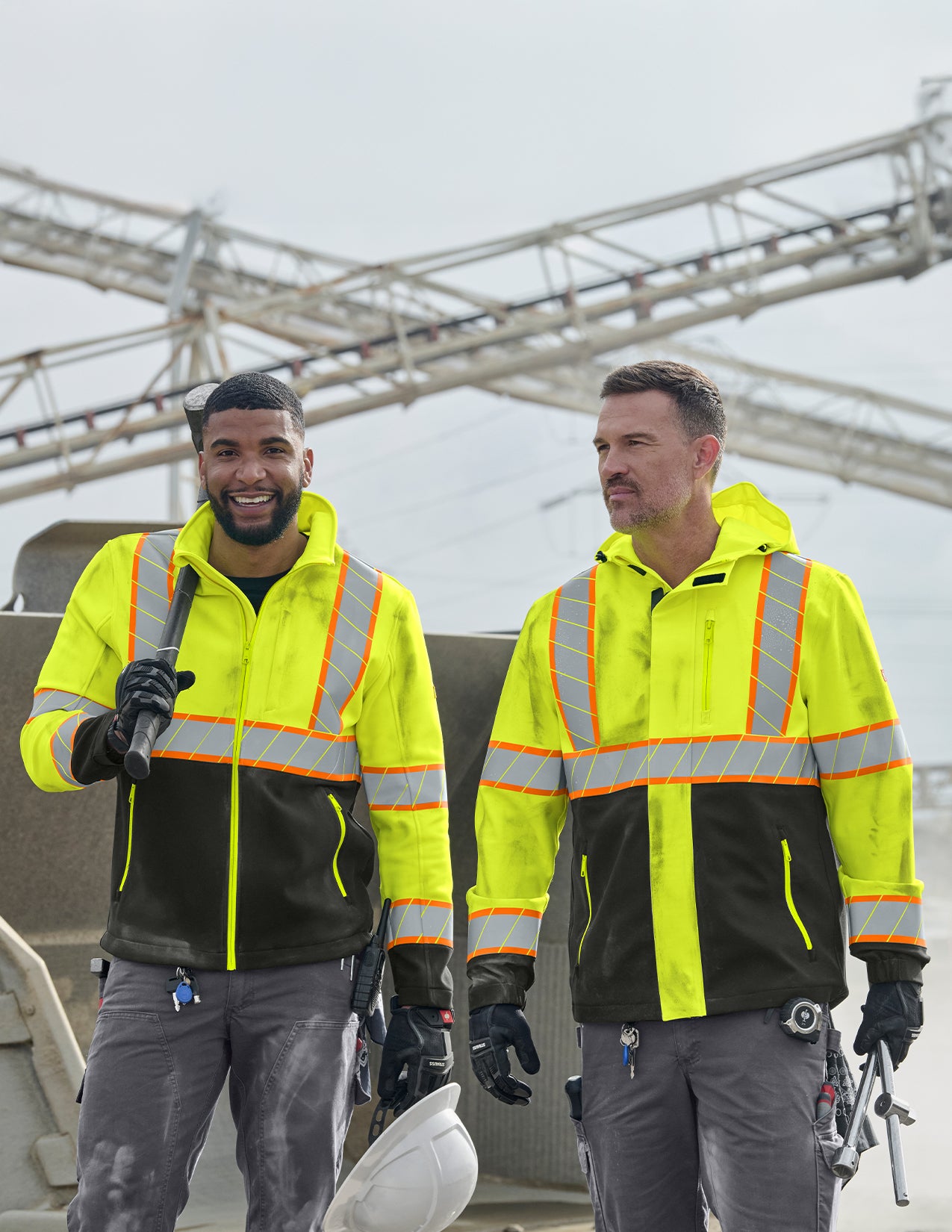 Two men wearing high-visibility safety jackets outdoors.